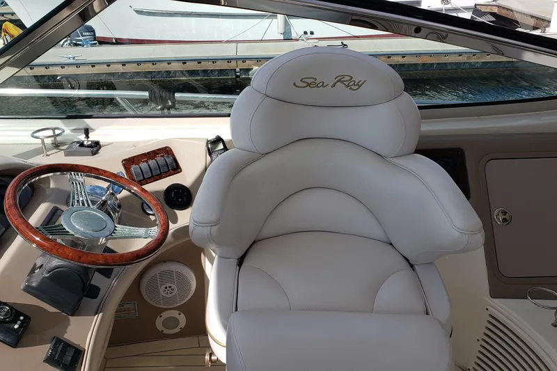 Slide: The Image of Captain's seat and helm of 2004 Sea Ray 550 Sundancer yacht, featuring luxurious white upholstery. - 23