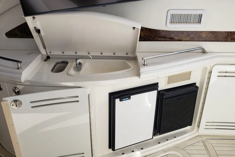 Slide: The Image of 2004 Sea Ray 550 Sundancer yacht kitchenette with sink, fridge, and storage compartments. - 30