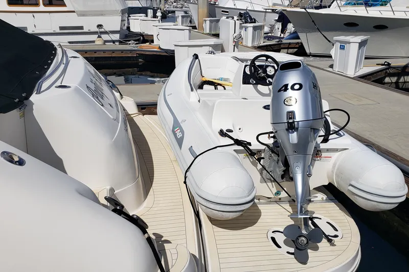 Slide: The Image of 2004 Sea Ray 550 Sundancer with inflatable boat and outboard motor at marina. - 99