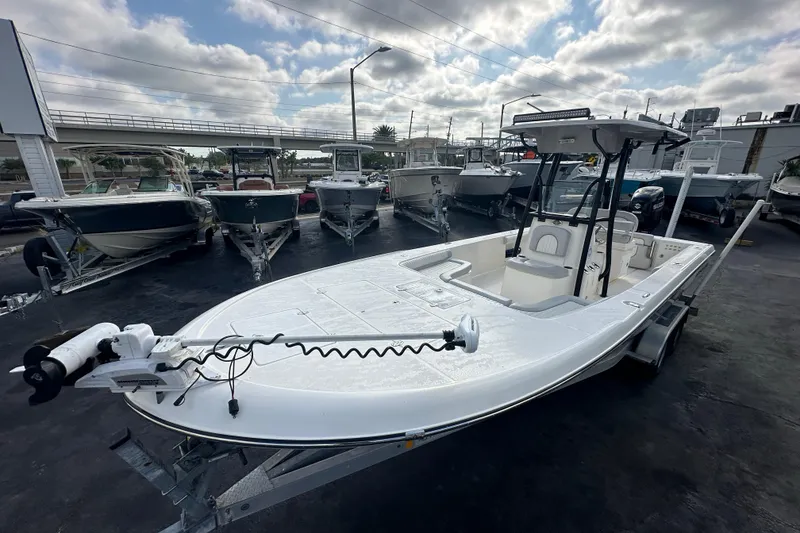 Slide: The Image of 2018 Sea Born FX25 Bay boat on trailer, parked among other boats under cloudy sky. - 13