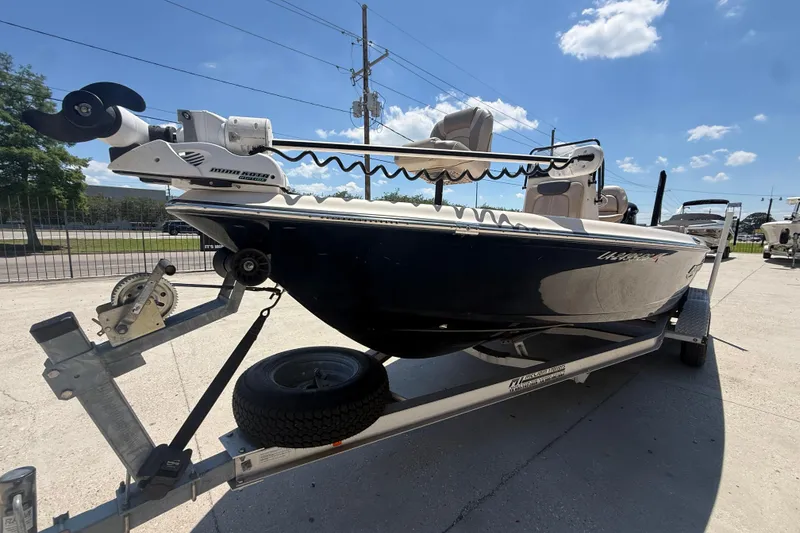 Slide: The Image of 2016 Blue Wave 2200 PureBay boat on trailer, featuring a trolling motor, under a clear sky. - 11