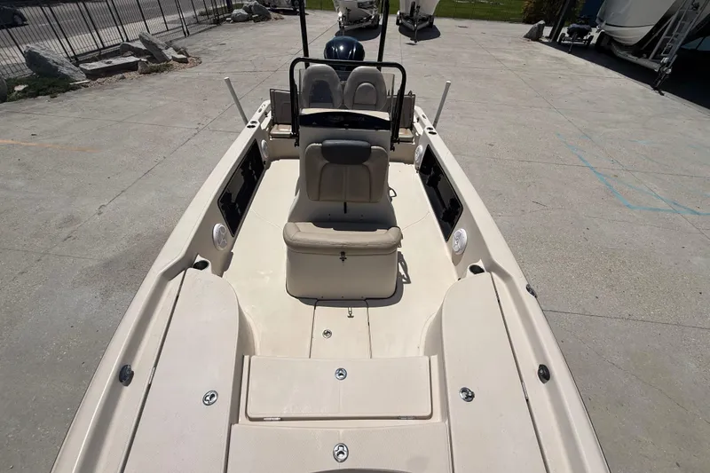 Slide: The Image of 2016 Blue Wave 2200 PureBay boat interior, featuring seating and console, parked on concrete. - 17