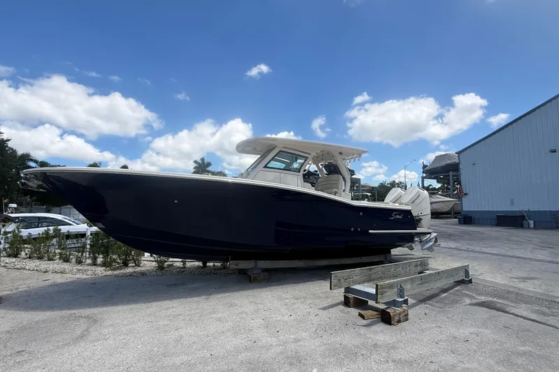 The Image of 2025 Scout 330 LXF boat displayed outdoors under a clear blue sky. - 1