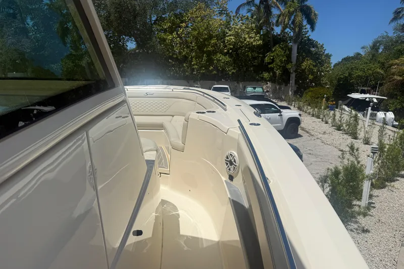 Slide: The Image of 2025 Scout 330 LXF boat with sleek design, parked outdoors under clear blue sky. - 14