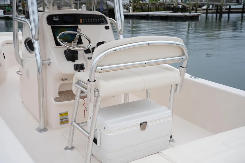 Slide: The Image of 2015 Grady-White 251 Coastal Explorer boat helm with seating and cooler on calm water. - 20