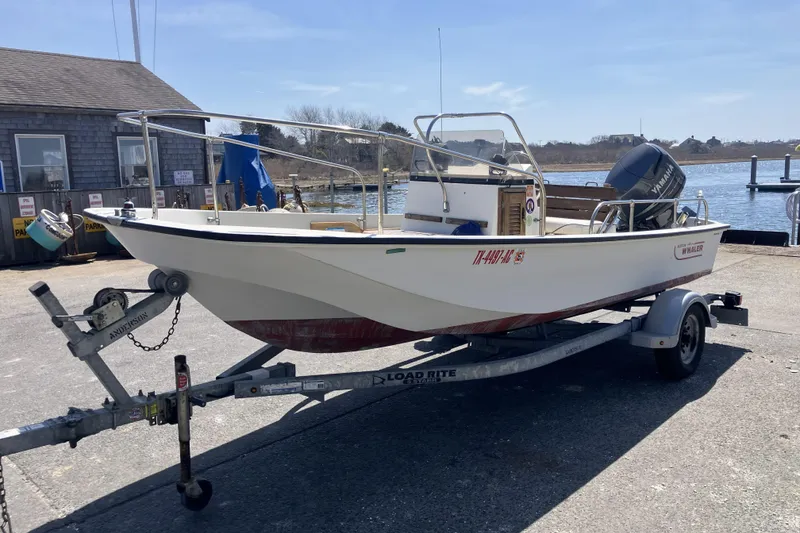 The Image of 1983 Boston Whaler 17 Montauk boat on trailer by waterfront dock. - 1