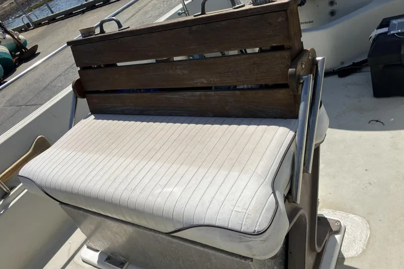 Slide: The Image of 1983 Boston Whaler 17 Montauk boat seat with wooden backrest and white cushion. - 21