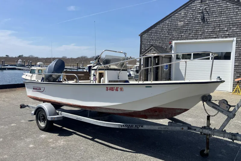 Slide: The Image of 1983 Boston Whaler 17 Montauk boat on trailer near marina and wooden building. - 4