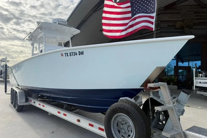 Slide: The Image of Custom 32 CC 2012 boat on trailer with American flag, parked outdoors. - 7