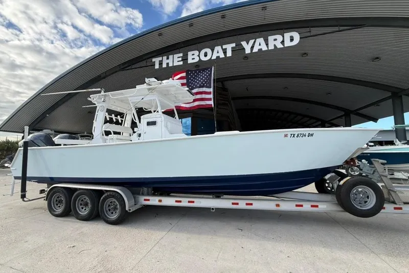 Slide: The Image of 2012 Custom 32 CC boat on trailer at The Boat Yard, American flag displayed. - 8