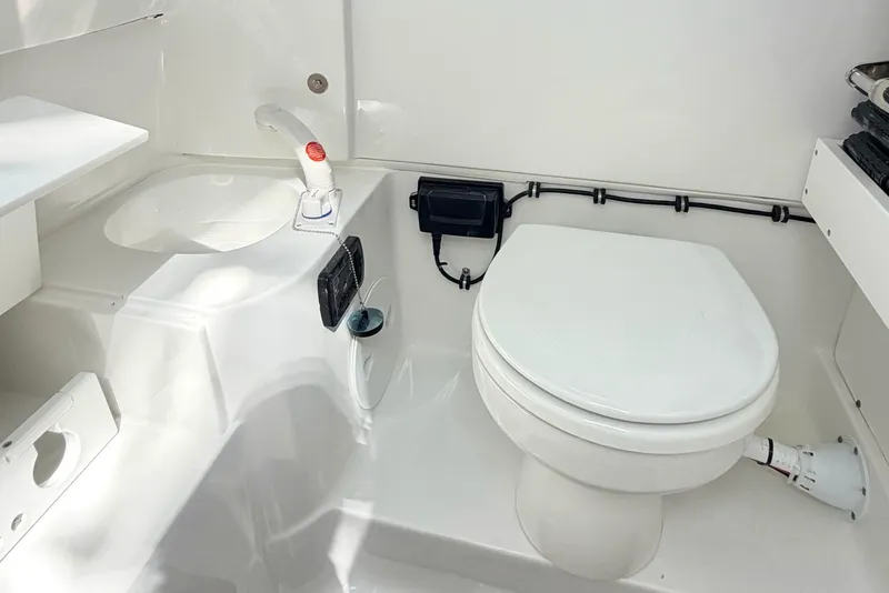 Slide: The Image of Interior of 2026 Sea Hunt Ultra 285 Coffin Box boat, featuring a compact marine toilet. - 24