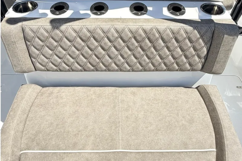 Slide: The Image of 2026 Sea Hunt Ultra 285 Coffin Box boat seating with diamond-pattern upholstery and cup holders. - 7