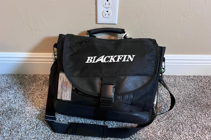 Slide: The Image of Blackfin branded black bag on carpeted floor, near wall outlet. - 19