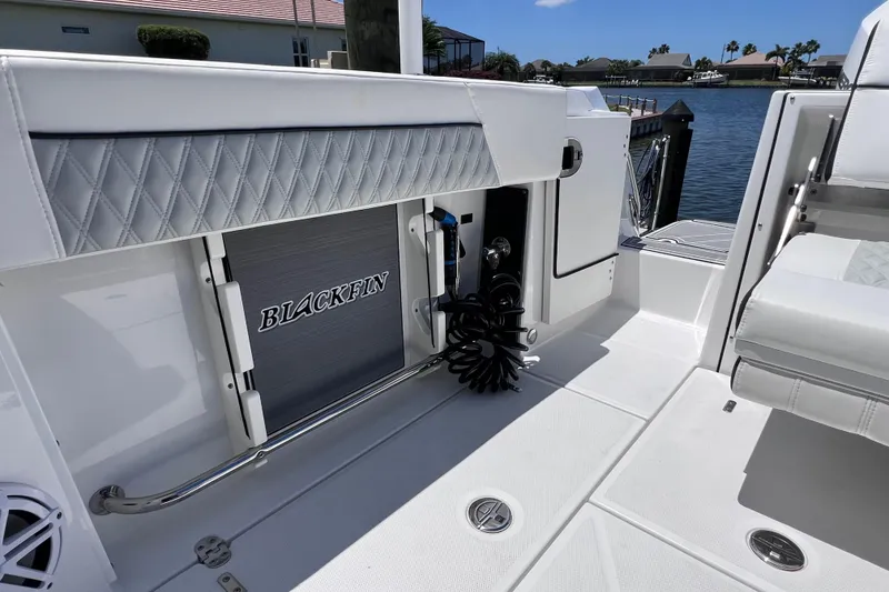Slide: The Image of 2023 Blackfin 272 DC boat interior with storage compartment and seating, docked by the water. - 34