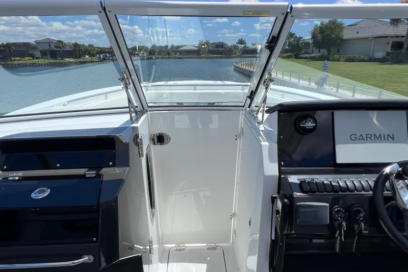 Slide: The Image of 2023 Blackfin 272 DC boat cockpit with Garmin navigation system, docked by a scenic waterfront. - 53