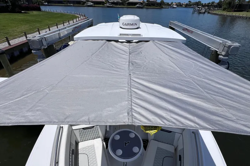 Slide: The Image of 2023 Blackfin 272 DC boat with sunshade and Garmin equipment on a calm waterway. - 82