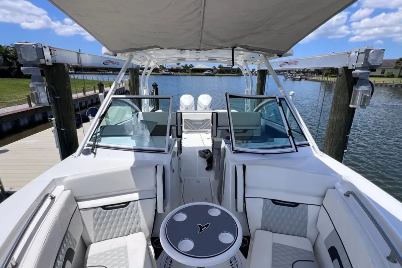 Slide: The Image of 2023 Blackfin 272 DC boat interior with seating and table, docked by the water. - 83