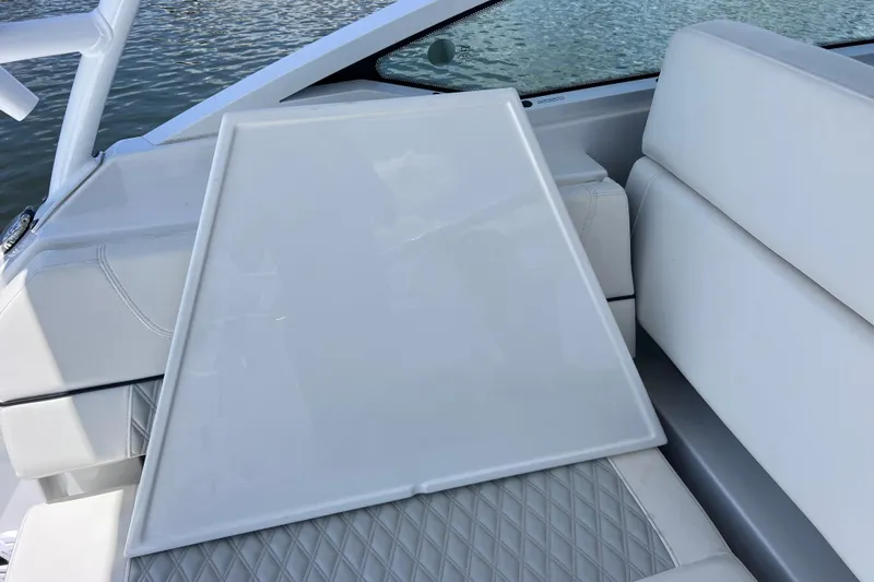 Slide: The Image of 2023 Blackfin 272 DC boat interior with white seating and table, near water. - 87
