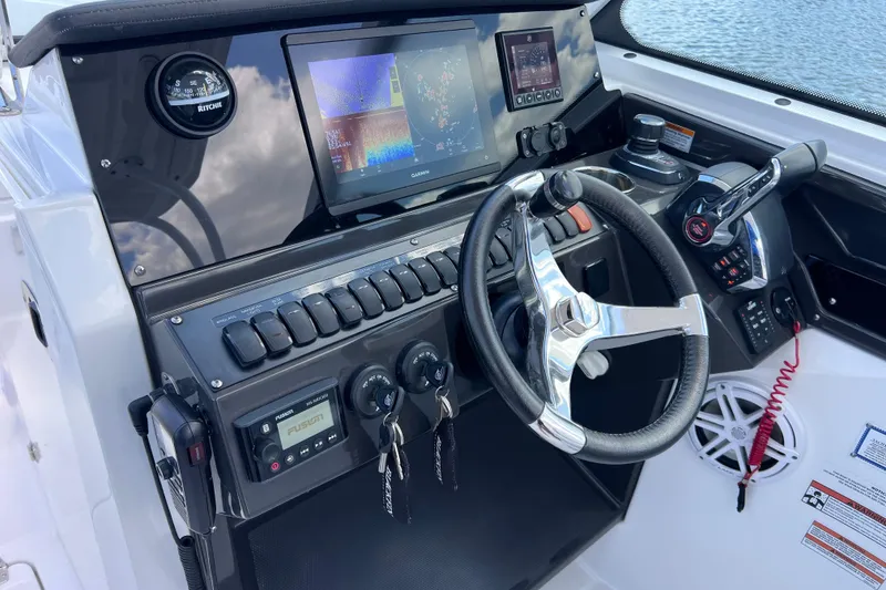 Slide: The Image of 2023 Blackfin 272 DC boat dashboard with steering wheel and navigation controls. - 89