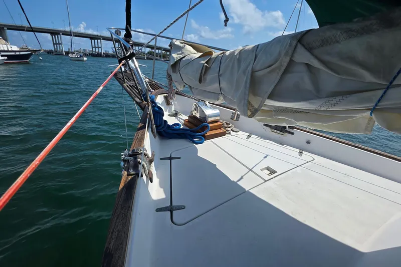 Slide: The Image of 1987 Gozzard 36 Cruiser sailboat deck with sails, docked near a bridge. - 12