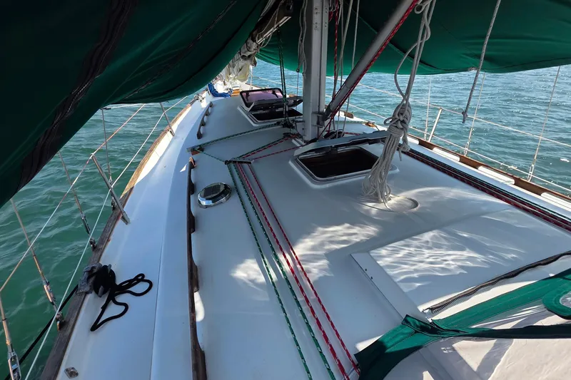 Slide: The Image of 1987 Gozzard 36 Cruiser sailboat deck with green sails and rigging on the water. - 16