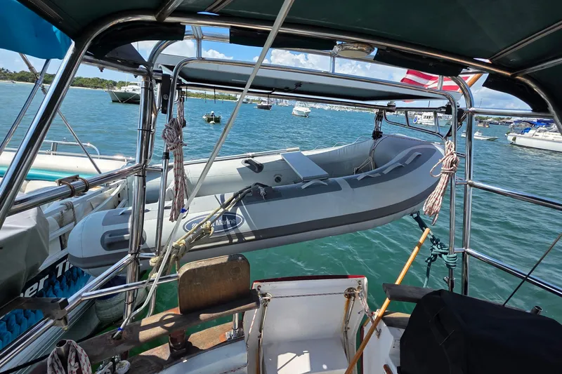 Slide: The Image of 1987 Gozzard 36 Cruiser with dinghy on davits, anchored in a scenic marina. - 19