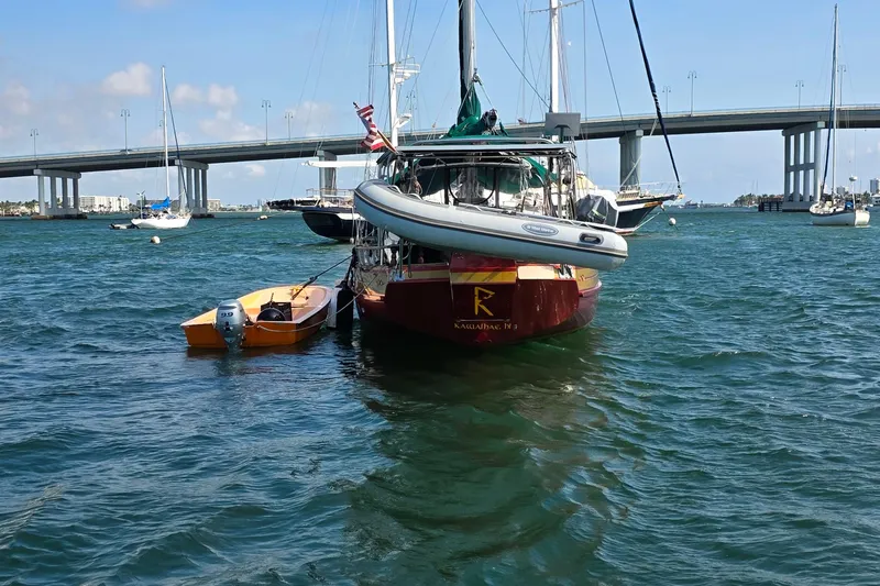 Slide: The Image of 1987 Gozzard 36 Cruiser sailboat moored near a bridge with dinghy attached. - 2