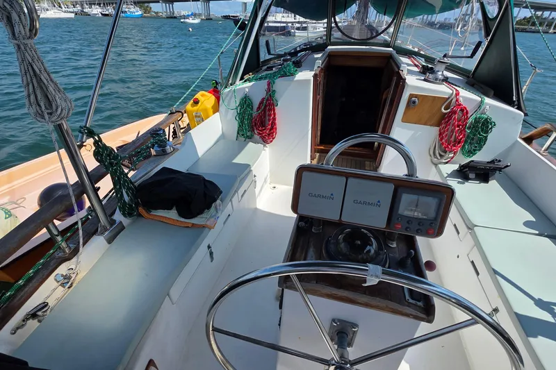 Slide: The Image of 1987 Gozzard 36 Cruiser cockpit with steering wheel, navigation equipment, and ropes on a sunny day. - 23