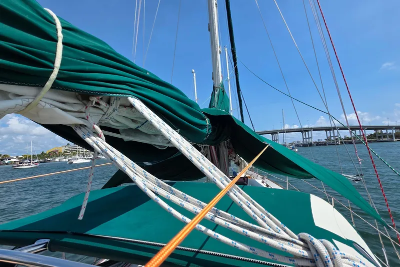 Slide: The Image of 1987 Gozzard 36 Cruiser sailboat with green sails docked near a bridge. - 24
