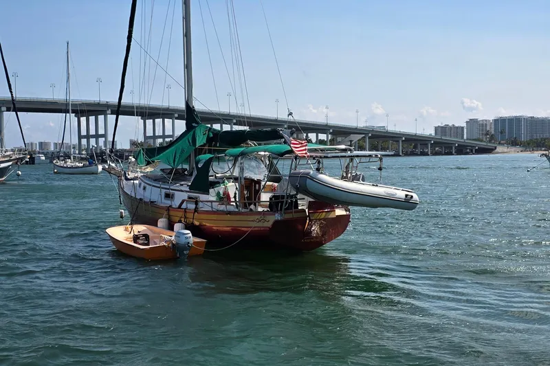 Slide: The Image of 1987 Gozzard 36 Cruiser sailboat anchored near a bridge, with dinghy attached. - 4