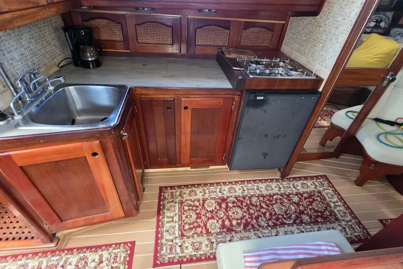 Slide: The Image of Interior of 1987 Gozzard 36 Cruiser with wooden cabinetry and compact kitchen setup. - 49