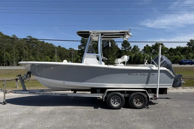The Image of 2015 Sea Hunt Ultra 211 boat on trailer, parked outdoors under clear sky. - 0