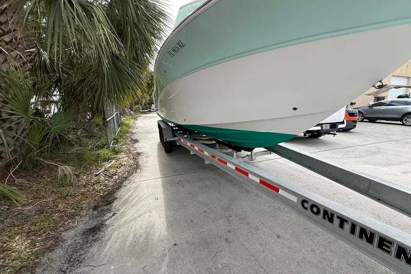 Slide: The Image of 2013 Sea Fox 286 Center Console boat on trailer, parked near palm trees. - 2