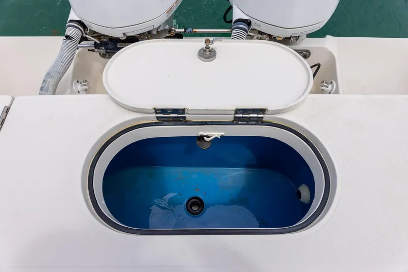 Slide: The Image of Open livewell on 2011 Jupiter 26 FS boat, showcasing interior and dual outboard motors. - 8