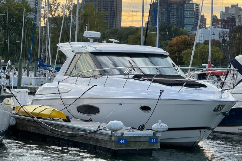 Slide: The Image of 2015 Regal 42 Sport Coupe yacht docked at marina with city skyline backdrop. - 2