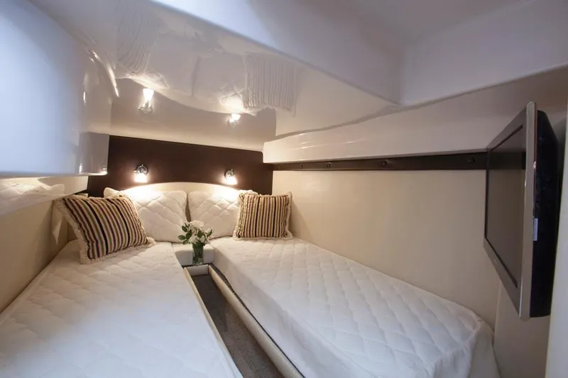 Slide: The Image of Manufacturer Provided Image: 2015 Regal 42 Sport Coupe cabin with twin beds, modern lighting, and striped pillows. - 29
