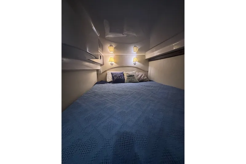 Slide: The Image of Cozy cabin interior of 2015 Regal 42 Sport Coupe with blue bedding and soft lighting. - 31