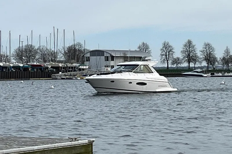 Slide: The Image of 2015 Regal 42 Sport Coupe cruising in a marina with sailboats and trees in the background. - 4