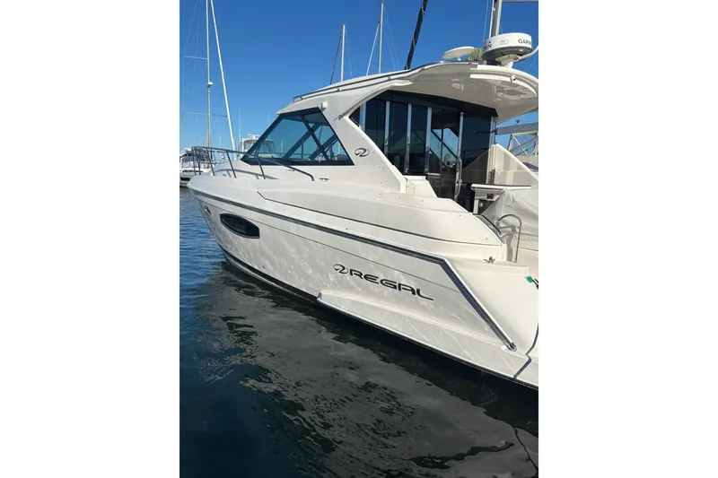 Slide: The Image of 2015 Regal 42 Sport Coupe yacht docked in marina under clear blue sky. - 6