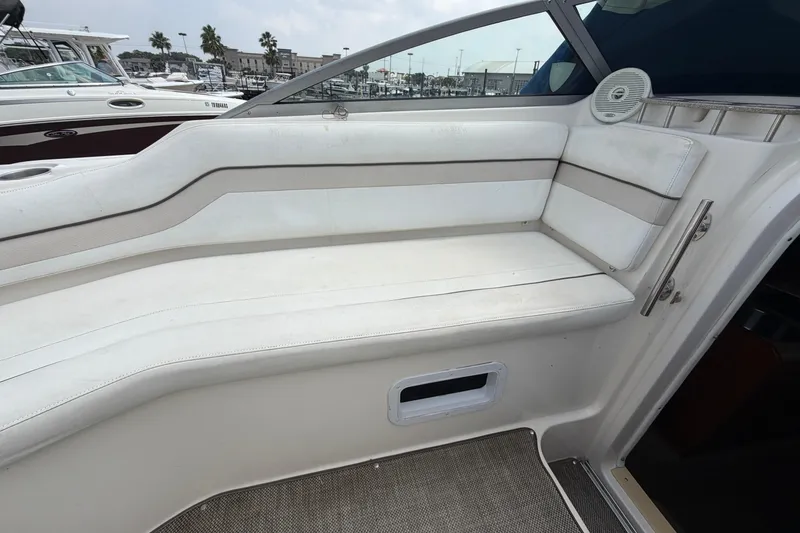 Slide: The Image of 2006 Rinker 250 Express Cruiser interior seating with white upholstery and marina view. - 11