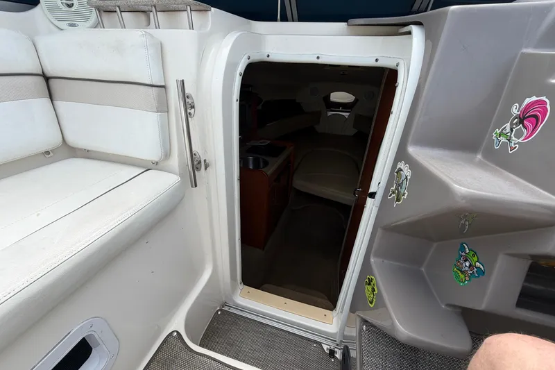 Slide: The Image of 2006 Rinker 250 Express Cruiser cabin entrance with seating and decorative stickers. - 12