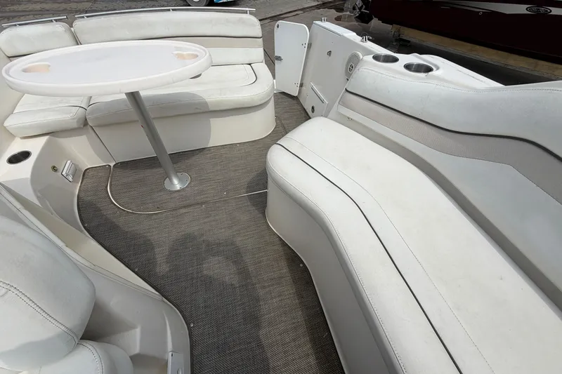 Slide: The Image of 2006 Rinker 250 Express Cruiser interior with white seating and round table. - 13