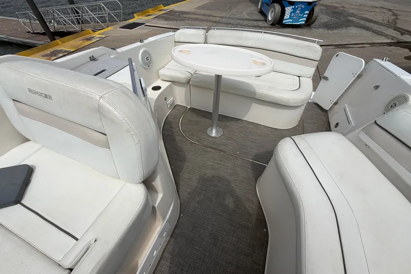Slide: The Image of 2006 Rinker 250 Express Cruiser interior with white seating and table, dockside view. - 14