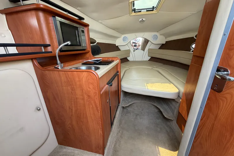 Slide: The Image of 2006 Rinker 250 Express Cruiser interior with kitchenette and cozy sleeping area. - 15