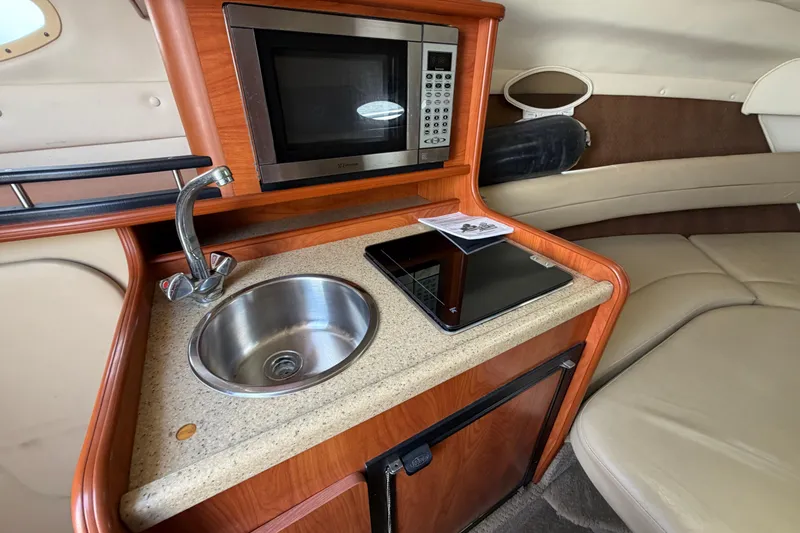 Slide: The Image of 2006 Rinker 250 Express Cruiser interior with kitchenette, sink, and microwave. - 18
