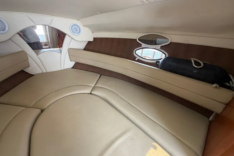 Slide: The Image of Interior cabin of 2006 Rinker 250 Express Cruiser with beige seating and porthole window. - 19