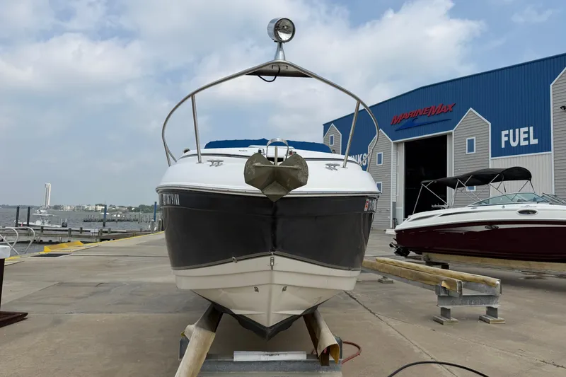 Slide: The Image of 2006 Rinker 250 Express Cruiser docked at a marina with blue building background. - 2