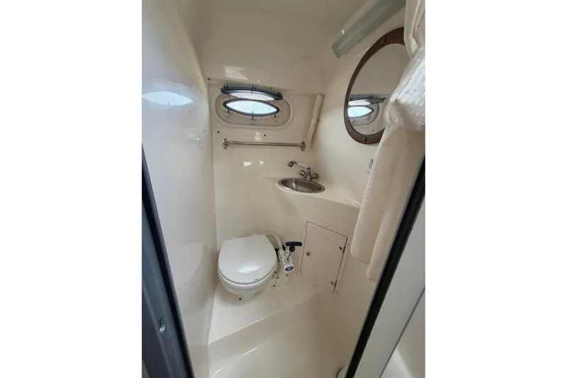 Slide: The Image of 2006 Rinker 250 Express Cruiser bathroom with toilet, sink, and porthole window. - 22
