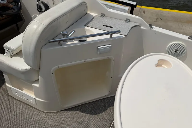 Slide: The Image of 2006 Rinker 250 Express Cruiser interior with seating and table, docked by the water. - 7