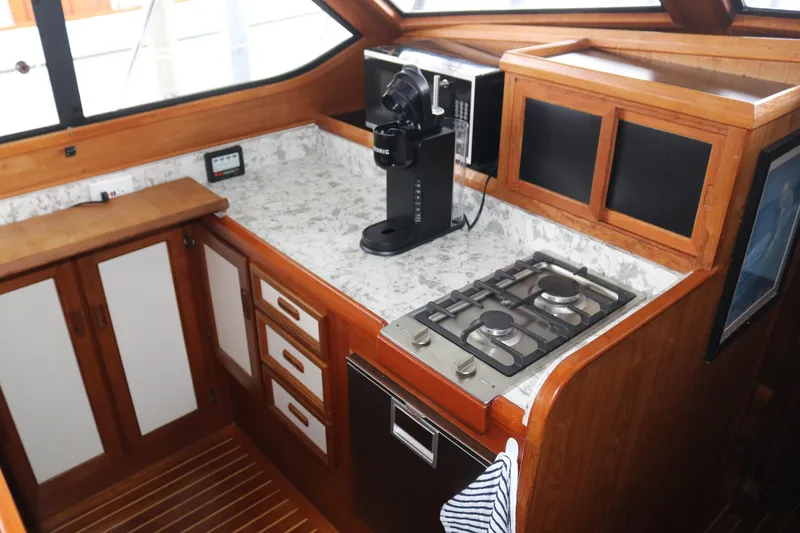 Slide: The Image of Compact boat kitchen with stove, coffee maker, and wooden cabinetry. - 47